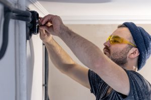 An Electrician Is Mounting Electric Sockets On The White Wall Indoors.