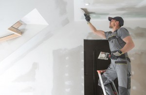 Pintor aplica rejunte e argamassa no teto branco