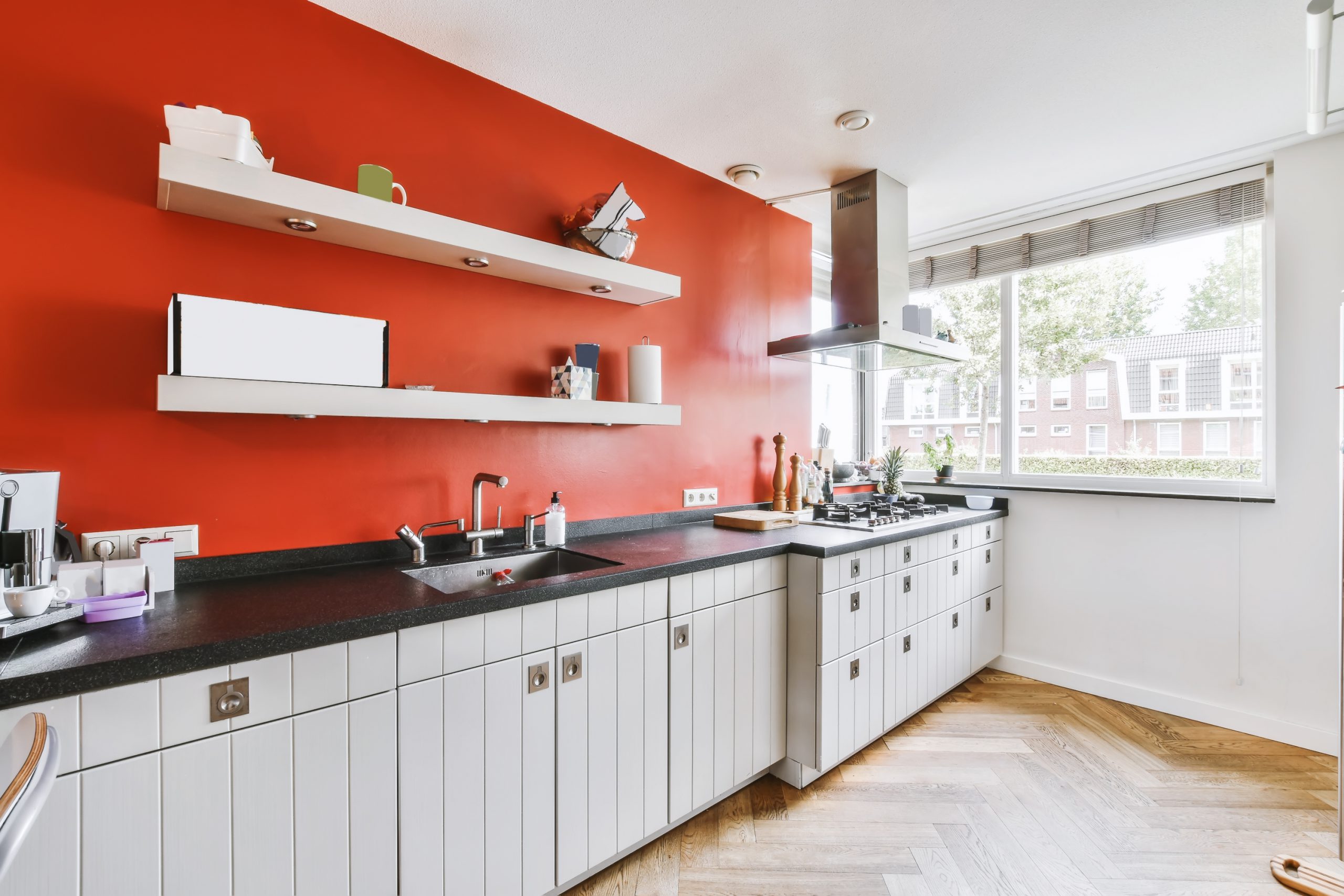 A Delightful Kitchen With A Red Wall And A White Kitchen Set