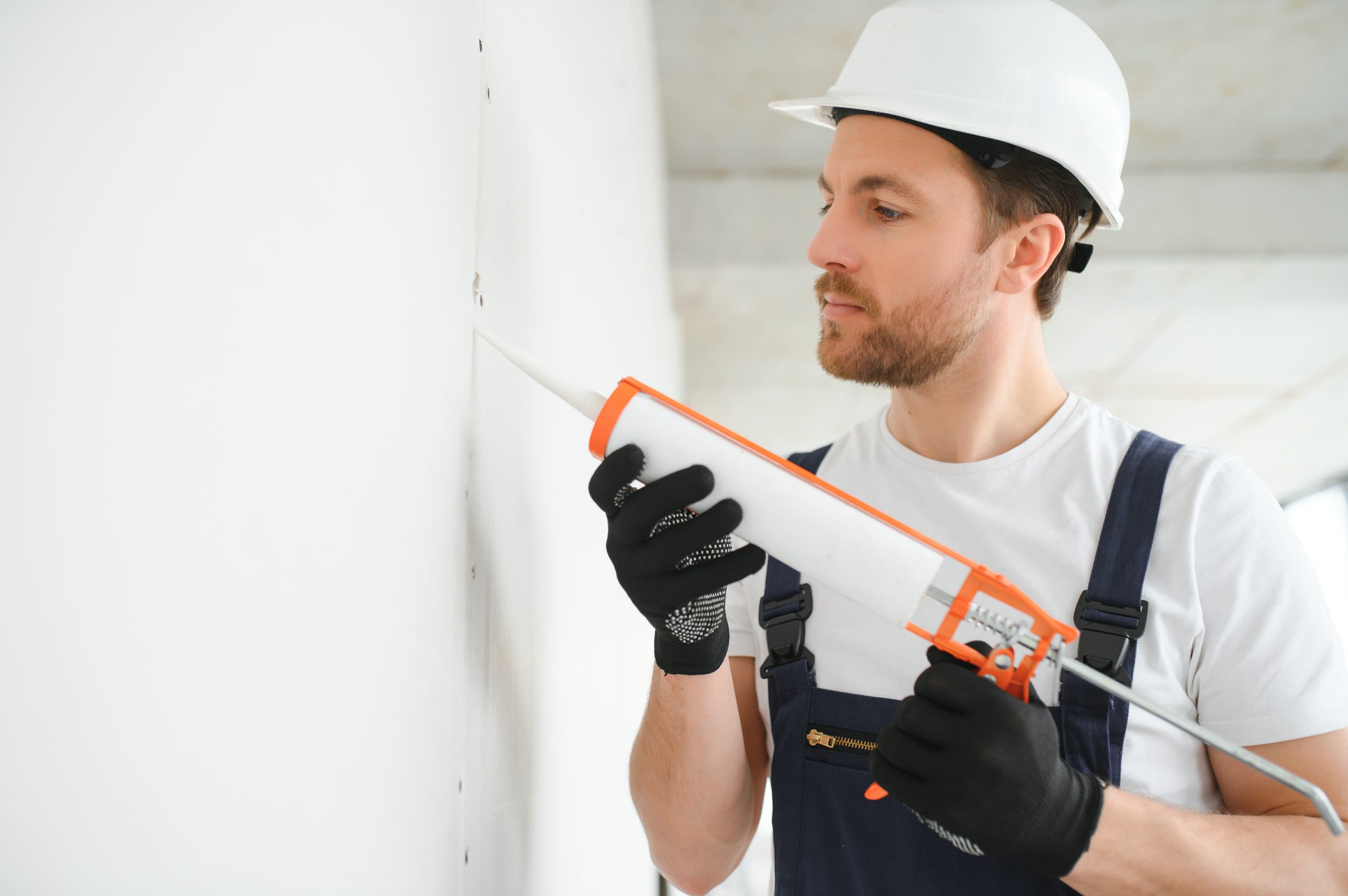 Professional Workman Applying Silicone Sealant With Caulking Gun On The Wall