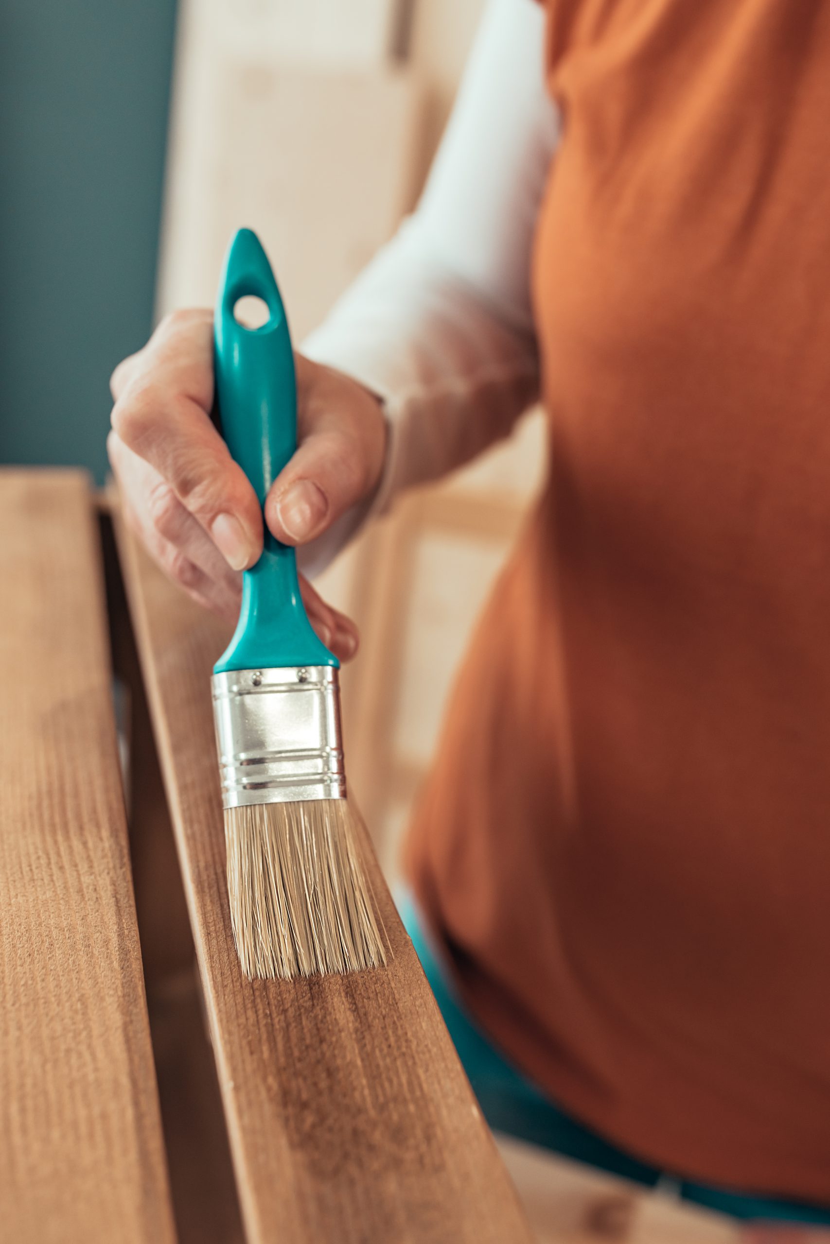 Female Carpenter Varnishing Wooden Crate With Brush