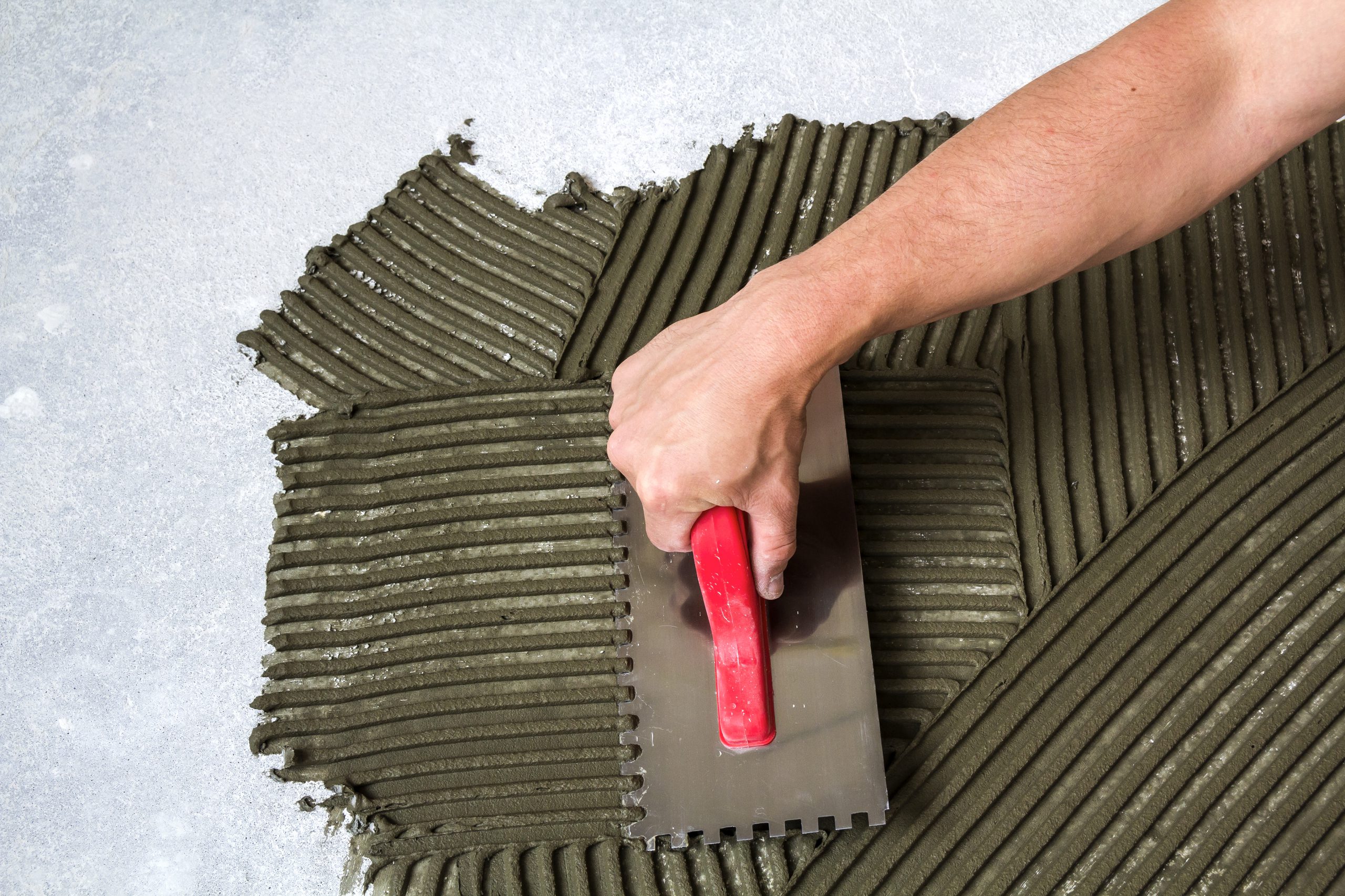 Worker Hand With Trowel Tool For Tiles Installation Making Mortar Adhesive On Floor