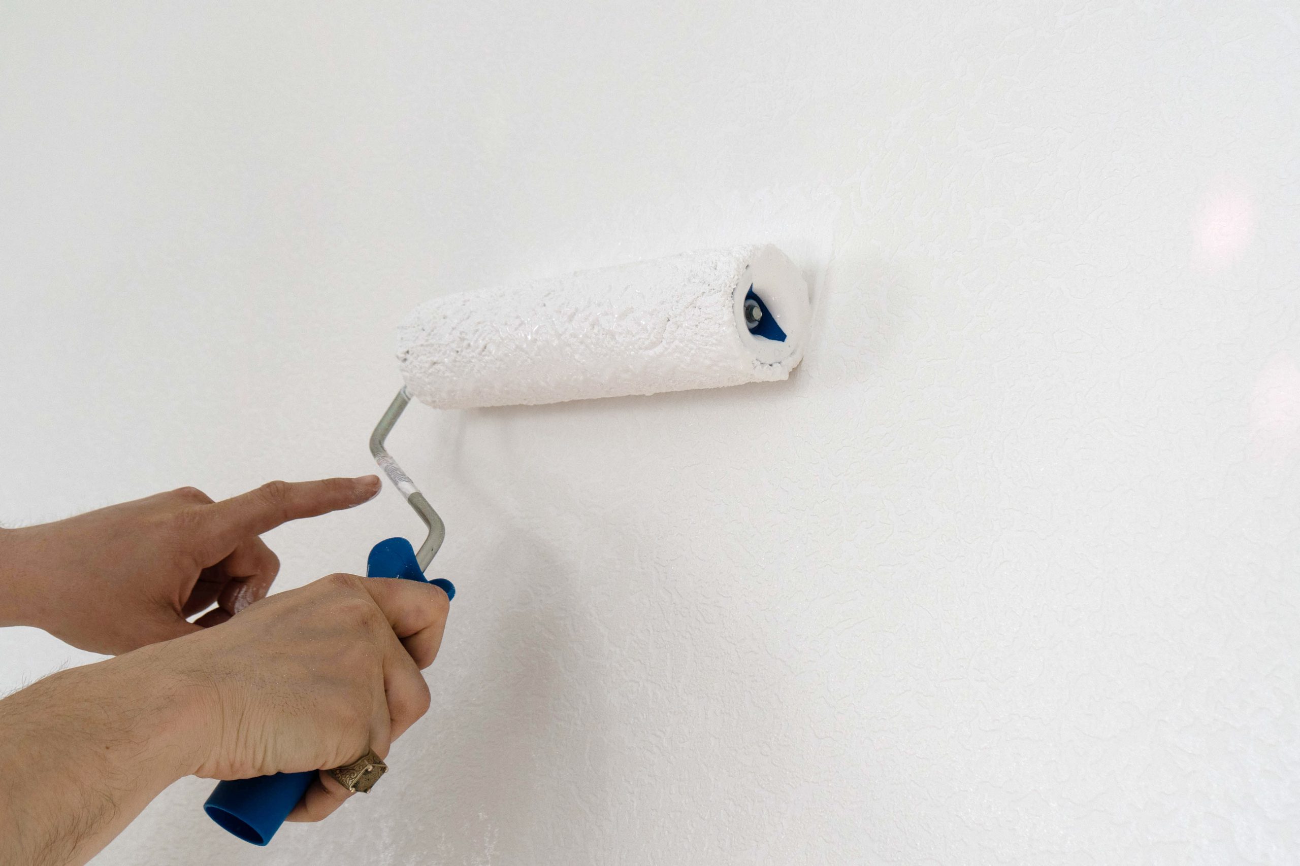 A Man Paints A Wall White With A Roller.