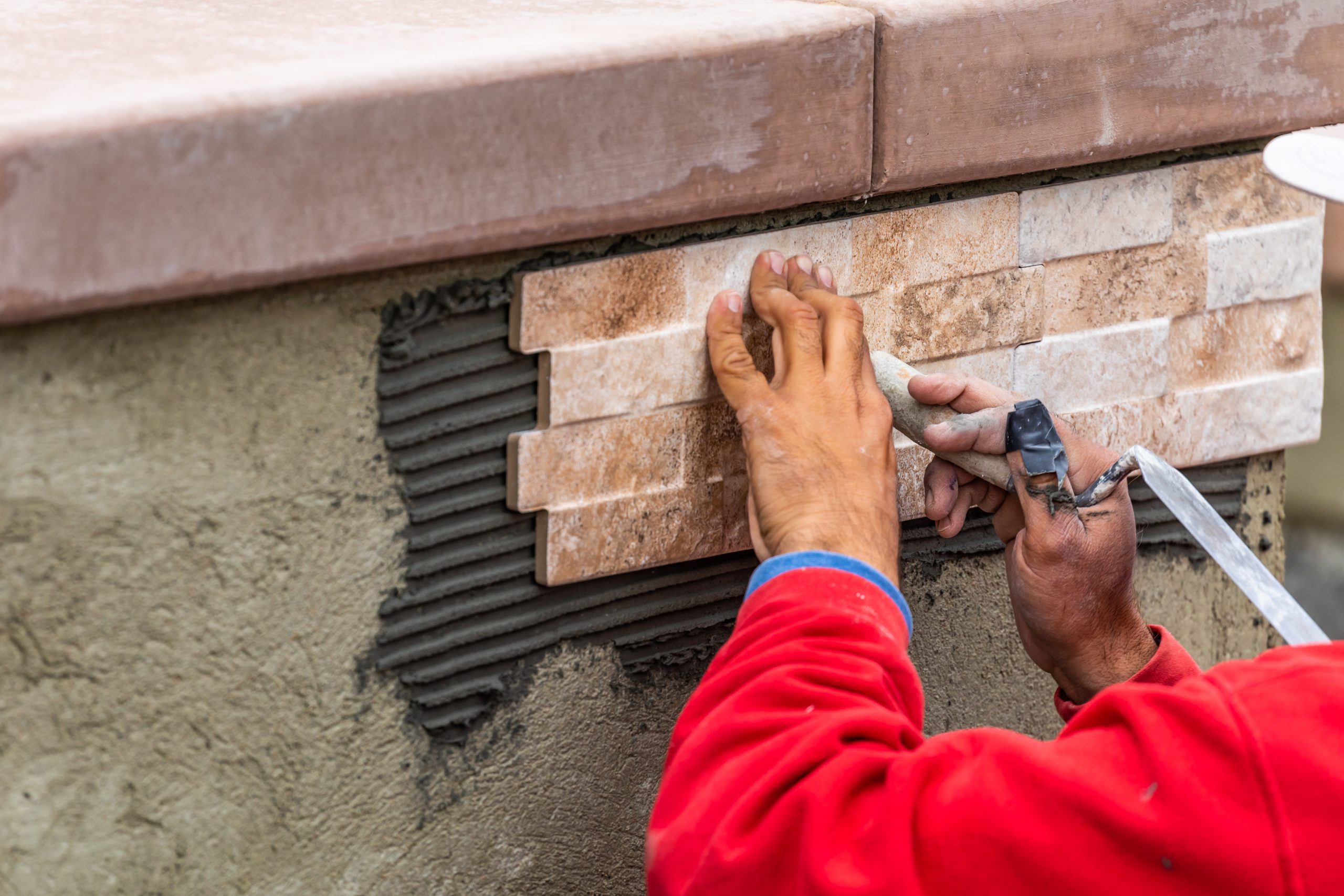 Worker Installing Wall Tile At Construction Site.